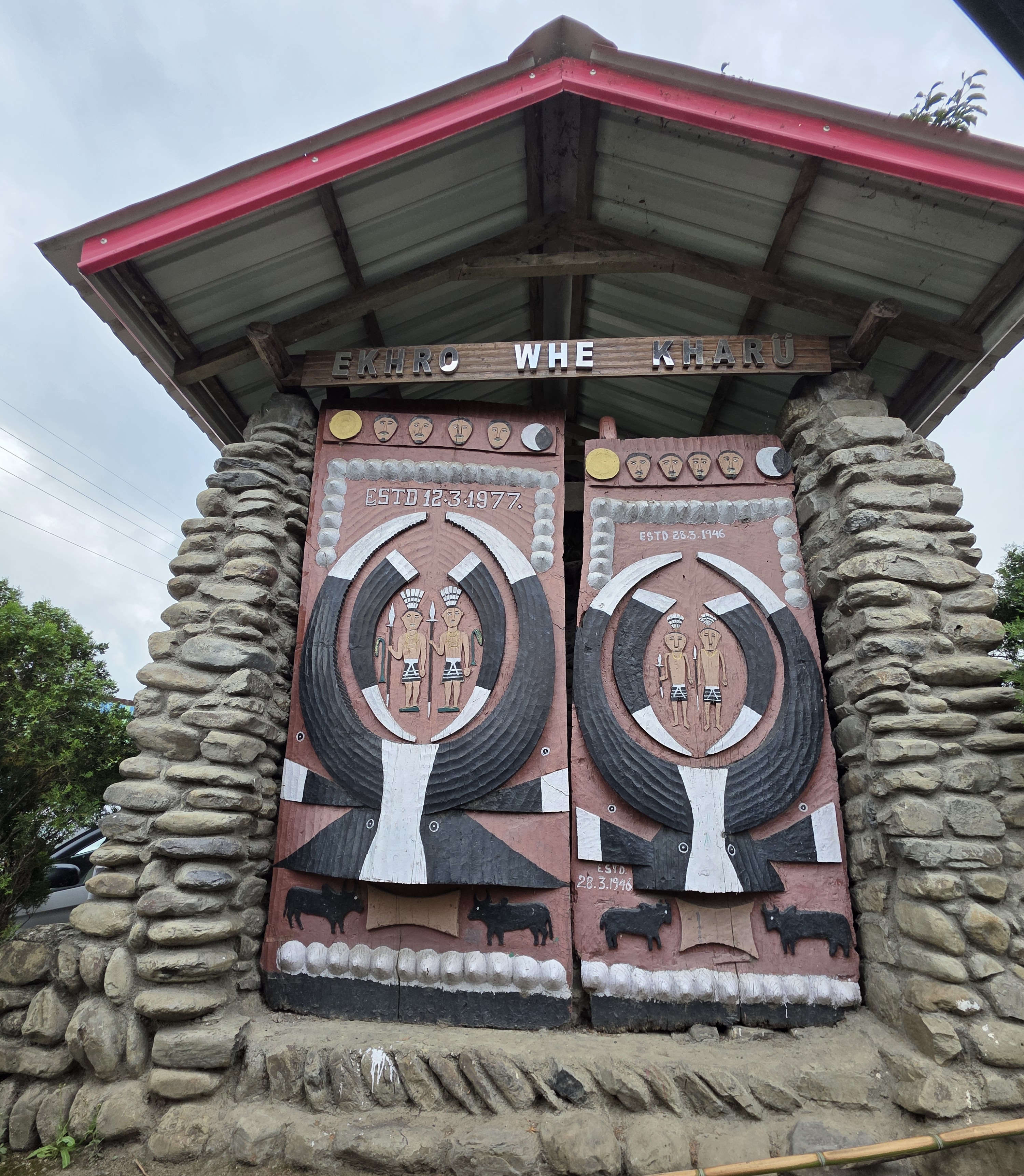 A traditional carved Angami village gate (kharü) at Viswema with warrior figures, mithun motifs, and stone pillars